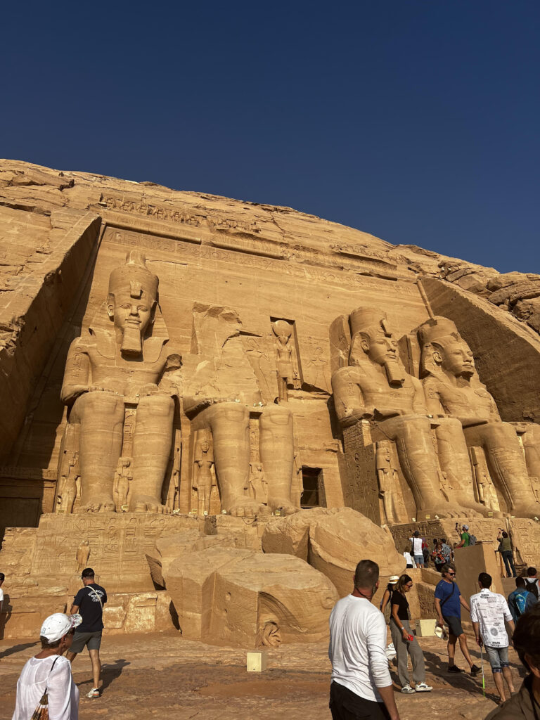 The pictures shows the entrance to one of the Abu Simbel temples with a crowd infront.