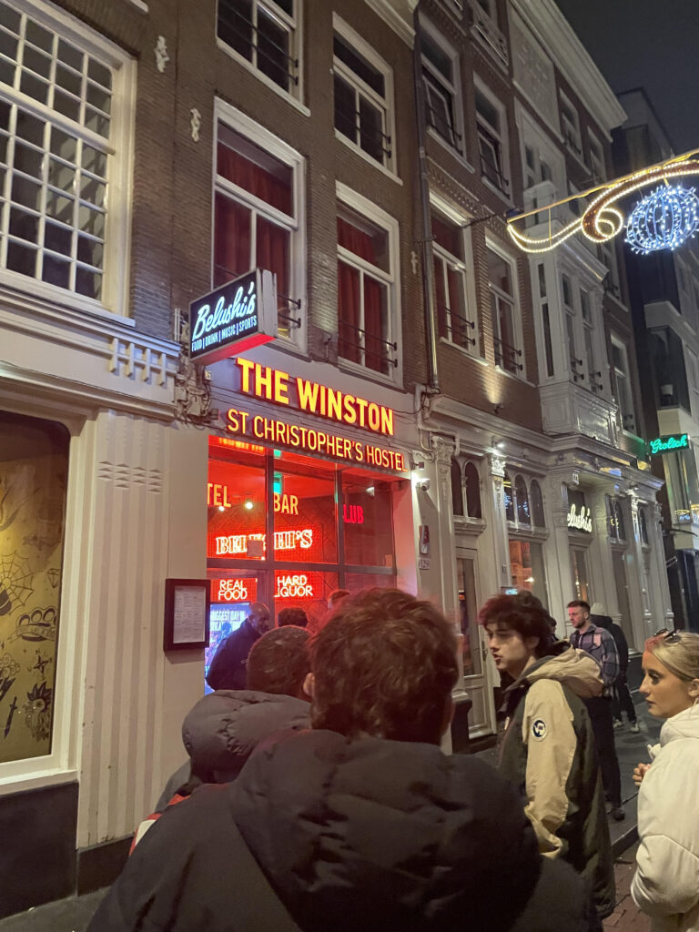 The image depicts the outside front of a hostel called 'The Winston' in Amsterdam