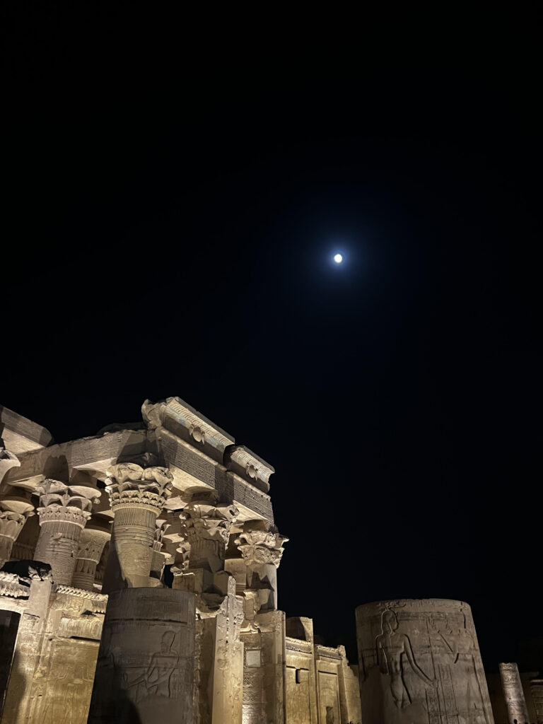 The front of Kom Ombo Temple with the moon in a clear night sky.