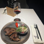 A picture of a steak with a glass of red wine.