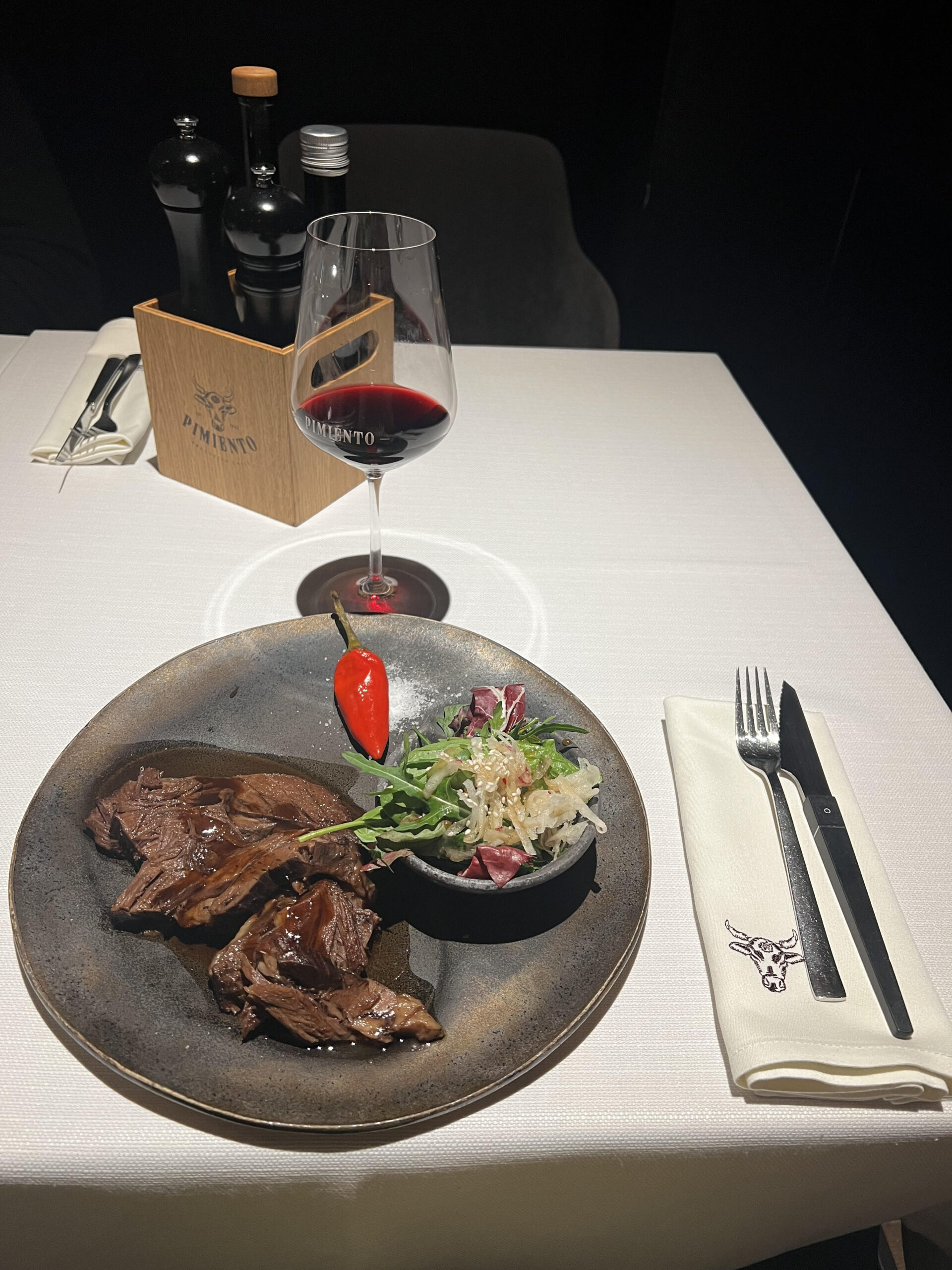 A picture of a steak with a glass of red wine.