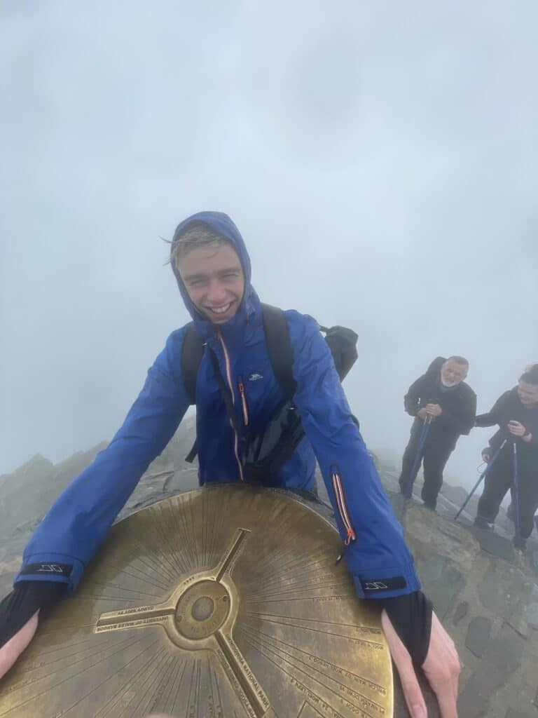 The author stood next to the peak of Snowdon in blustery, windy conditions