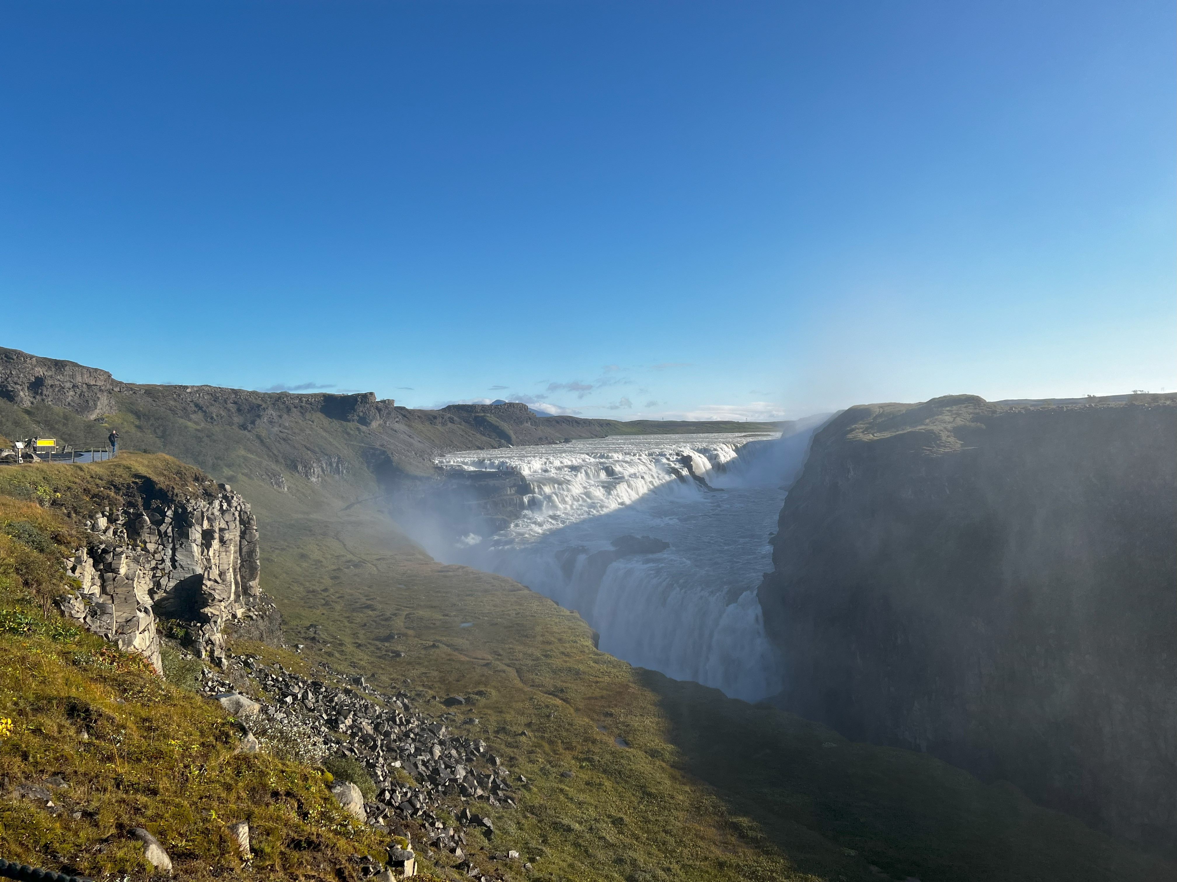 A landscape view of the pretty Gullfoss waterfall with steam emerging.