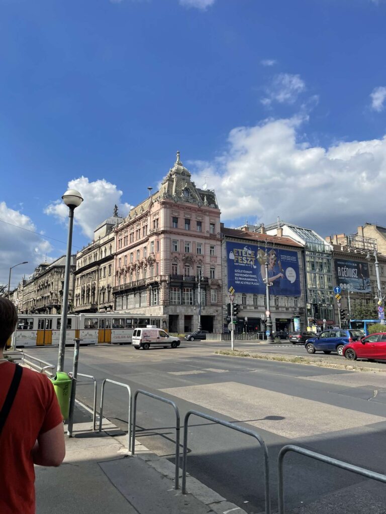 A part of Budapests city centre with cars, trams and building's visible.