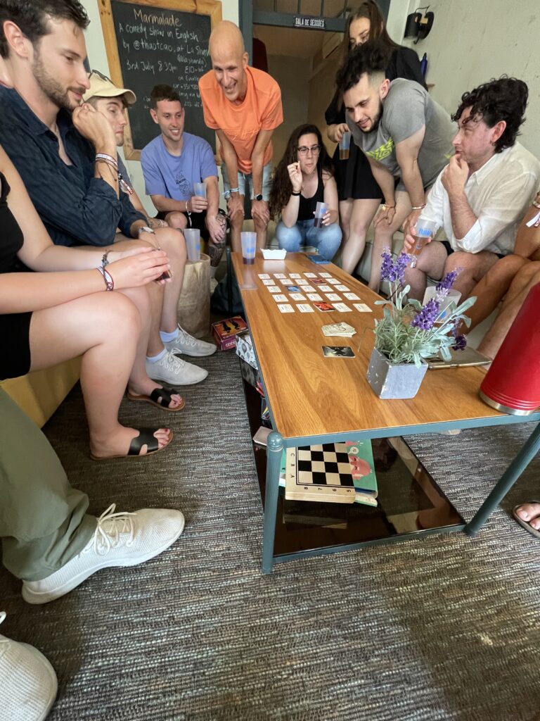 Numerous people sat around playing a card game at the hostel in Lisbon