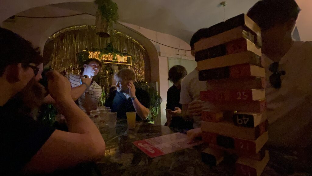 A group of lads in a bar playing jenga at the start of an evening.