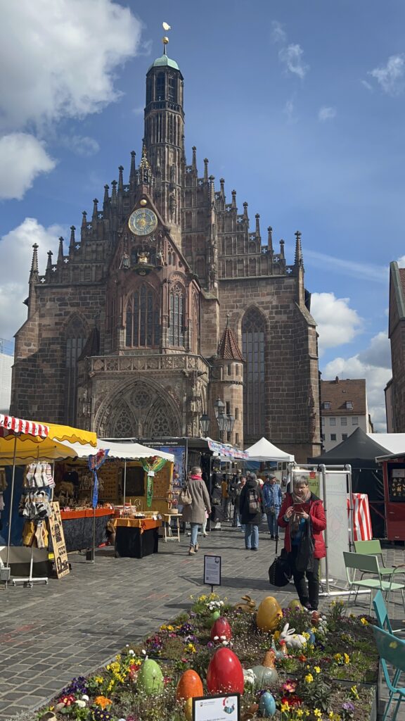 A portrait image of the Hauptmarkt (market) with the Frauenkirche in the background.